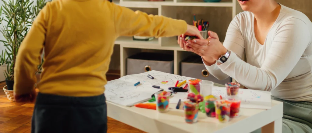 Mamá e hijo dibujando con crayones en casa